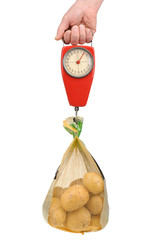 Hand holding a spring scale with a bag of potatoes isolated on white