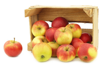 Fresh red and yellow apples in a wooden crate on a white background
