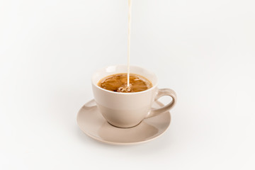 Close-up view of milk pouring into cup of coffee isolated on white