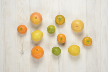 Naklejka na ściany i meble Cítricos sobre fondo de madera blanca. Naranja, mandarina, pomelo, limón y lima.