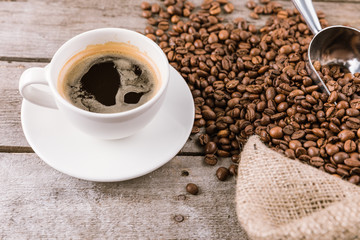 close up view of coffee mug steam and beans with scoop on sack cloth