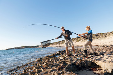 Senior man fishing with his grandson