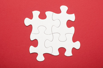 Four white puzzle pieces on red background