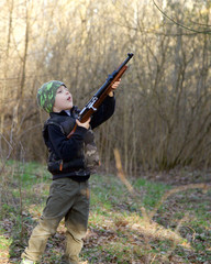 Cute  child in soldier uniform playing toy gun outdoors