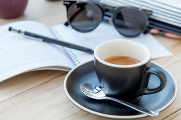 Hot coffee in black cup with book sunglass in the living room