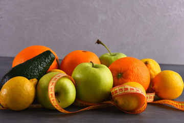 various fruits: lemon, apple, orange, avocado, grey studio wall background