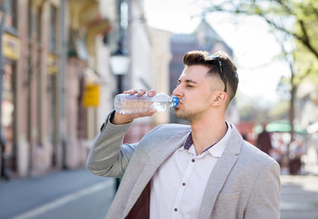 young business man drinking watyer from bottle on a street