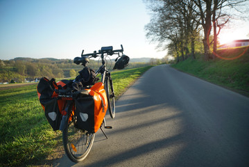 Bike with bags, helmet and smartphone case parking by the roadside during tour