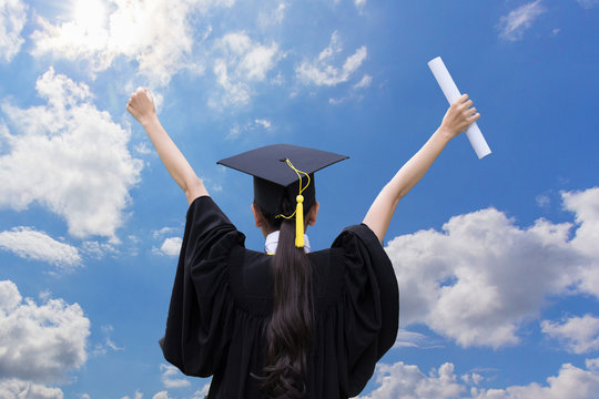 Graduate celebrating with certificate in her hand with blue sky background,Back of view