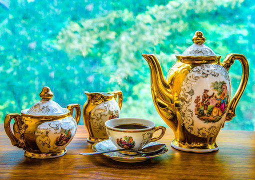 On the background of green foliage elegant coffee service: teapo