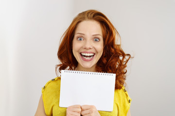 lachende frau mit roten locken zeigt eine leere seite