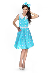 Beautiful girl in a polka-dot dress with a blue bow on a white background