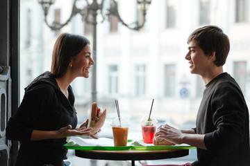 Smiling young man sitting in cafe with sister drinking juice