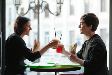Happy young man sitting in cafe with sister drinking juice