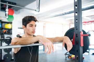 Hispanic man in gym resting, earphones in his ears,listening mus
