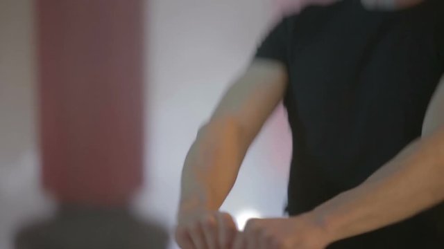 Ragazzo giovane con maglia nera si sta allenando in palestra con la kettlebell  giallo. Fumo per sfondo.