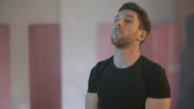 Ragazzo giovane con maglia nera si sta allenando in palestra con la kettlebell  giallo. Fumo per sfondo.