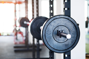 Metal heavy barbell in holder in modern gym.