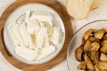 Fried young potatoes with cow cheese on the plate