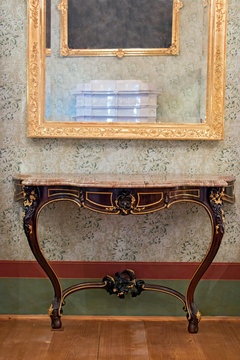 Historical table under the mirror in a gilded frame
