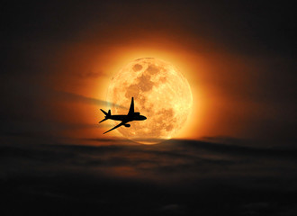 Silhouette airplane flying across the moon