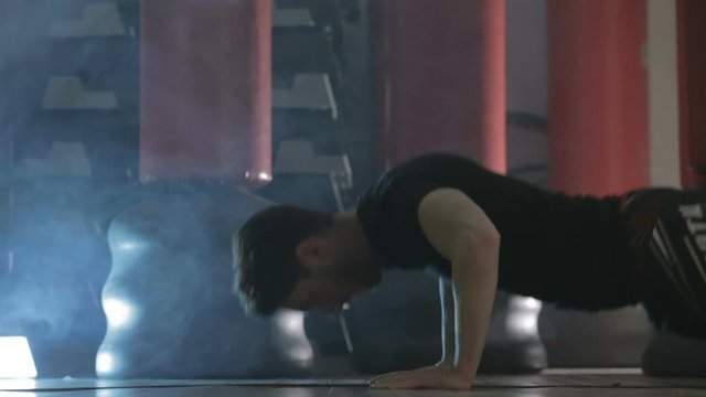 Ragazzo con maglietta nera si sta allenando in palestra con i piegamenti a terra