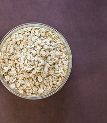 Food. Oatmeal on the table. Dry rolled oat flakes oatmeal in brown bowl on old wooden table.