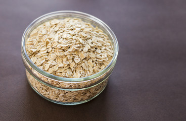 Food. Oatmeal on the table. Dry rolled oat flakes oatmeal in brown bowl on old wooden table.