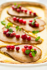Tart with roasted pears over rikotta cream decorated cranberries and mint leaves on blue wooden table. Selective focus