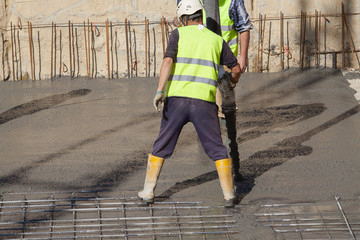 Lavoratori posano colata di cemento o calcestruzzo con pompa automatica

