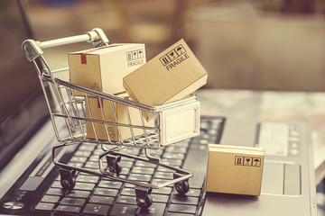 Paper boxes in a shopping cart on a laptop keyboard. Ideas about e-commerce, e-commerce or...