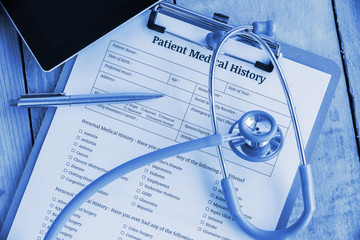 Patient medical history on a clipboard with stethoscope and a blue ballpoint pen, putting on a...