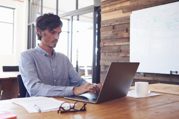 Mid-adult white man working in an office using laptop