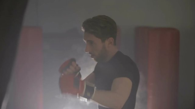 Uomo sportivo si allena in palestra al sacco da boxe.