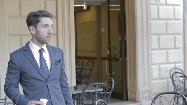 Uomo d'affari esce dal bar con un caff&egrave; in giacca e cravatta.