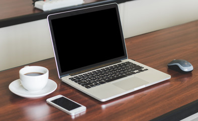 laptop, cell phone, coffee cup on wood table background in office.