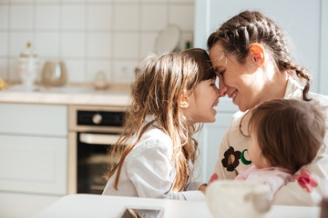 Young woman hugging her daughters