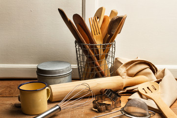 Utensilios de cocina, de madera, junto a una taza, una servilleta y cucharas sobre una mesa de...