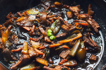 Stir fry, vegetables and meat, in a black pan 