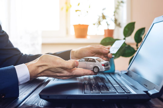 Man in the suit working in the office at a laptop, holding a car paying with a credit card