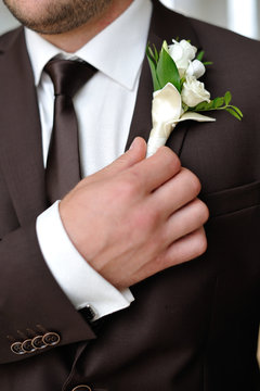 The groom holds his boutonniere hand