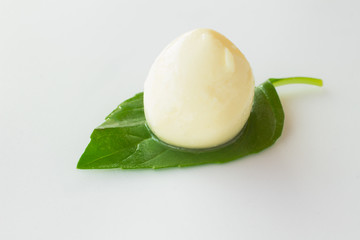 ball of mozzarella on a green leaf on a white background