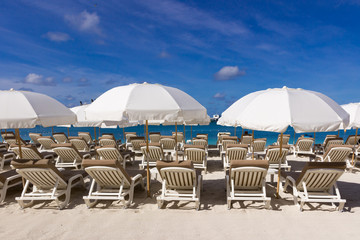  beach chairs and  white umbrellas on caribbean coast