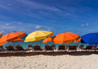 Colorful beach chairs and umbrellas on white sand caribbean coast