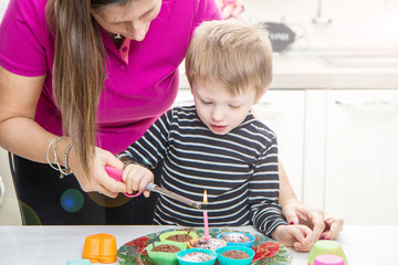 Fototapeta premium bambino e mamma che accendono la candelina di compleanno su dei muffin 