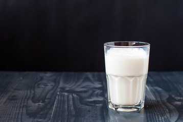 A glass of milk on a dark background. Milk in a glass on a wooden table.