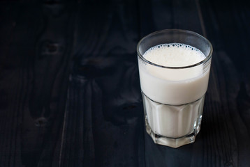 A glass of milk on a dark background. Milk in a glass on a wooden table.