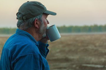 Senior farmer contemplating field with coffee in morning - Powered by Adobe