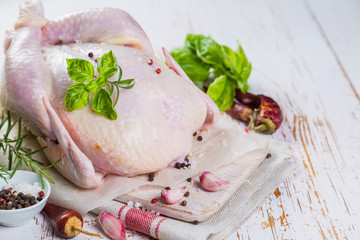 Raw whole chicken with herbs and spices on rustic wood background