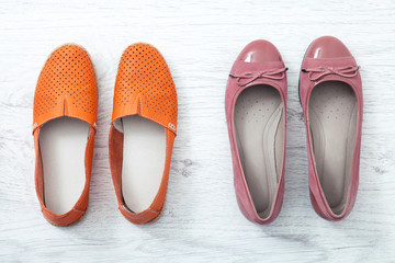 Flat lay fashion set: colored slippers shoes on white wooden background. Top view.
